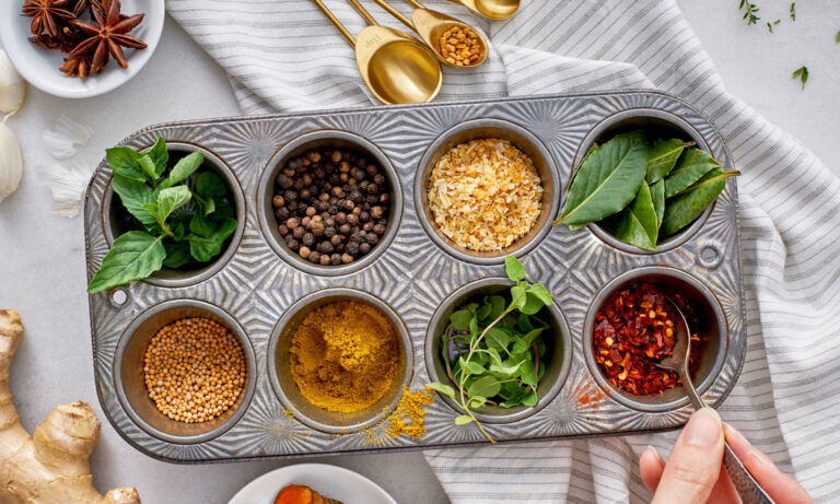 A colorful assortment of seven fat-fighting spices—turmeric, cinnamon, cumin, ginger, black pepper, fenugreek, and cayenne—arranged neatly in bowls.